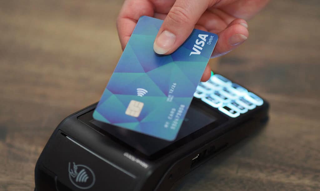 Hand, die eine SocialCard ans Kartenlesegerät hält, um zu bezahlen